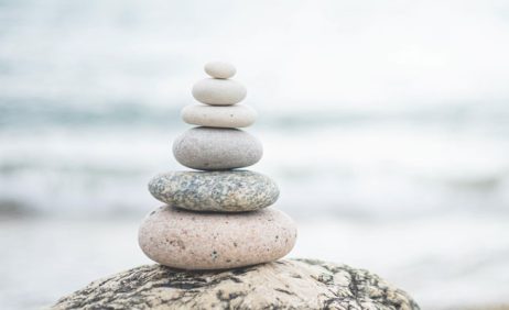 Stacked balancing stones on a rock beside calm water